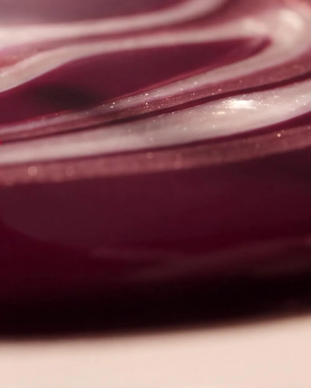 Spirale de vernis nacré dans une laque cerise, gros plan